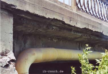 Auf der Unterseite der Brücke aus Beton fehlt bereits die Betonabdeckung. Das Bewährungseisen ist freigelegt.